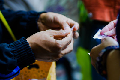 Cropped image of people holding paper while standing outdoors