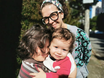 Mother, daughter and brother hugging on summer day.