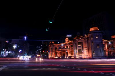 Light trails on road against buildings at night