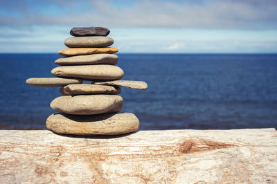 Stack of stones in sea against sky