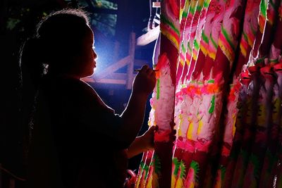 Side view of woman holding multi colored umbrella