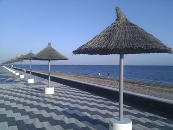 Lounge chairs at beach against clear blue sky