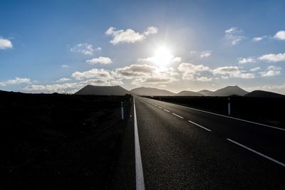 Road leading towards mountain against sky evening sun