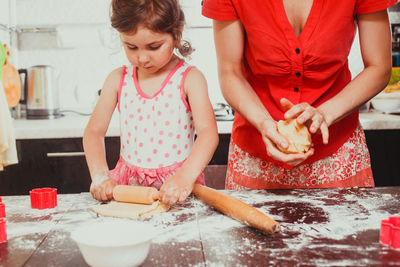 Cute girls preparing batter of cookies at home