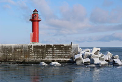 Lighthouse by sea against buildings