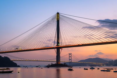 Low angle view of suspension bridge against sunset sky