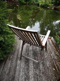 Empty bench on pier by lake