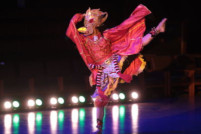Woman dancing against illuminated lights at night
