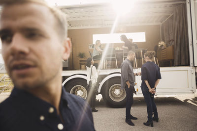 Business people discussing while standing by portable office truck on road