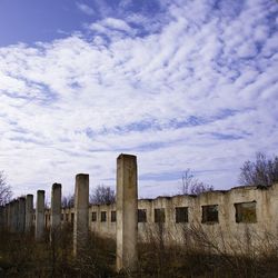 Wooden posts on field by buildings against sky