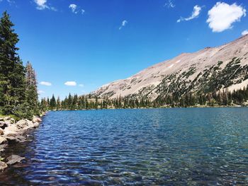 Scenic view of lake and mountains against blue sky