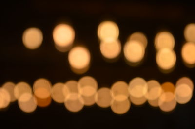 Defocused image of illuminated light bulb against black background