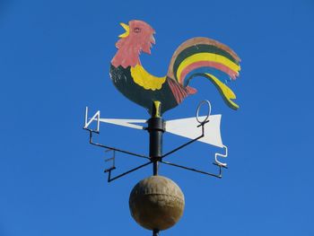 Low angle view of weather vane against clear blue sky