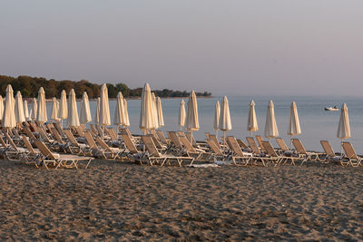 Deck chairs arranged on sand against sea at beach