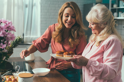 Cheerful mother and daughter making muffins at home