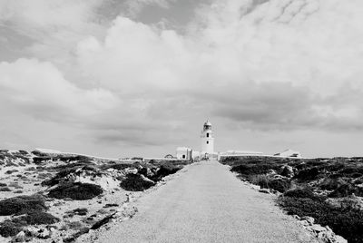 Lighthouse on landscape against cloudy sky