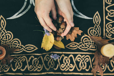 Cropped hands of person holding fruits and leaves on sheet