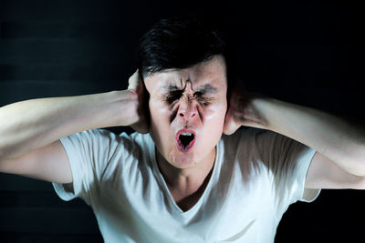 Man covering ears against black background