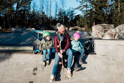 Mom and her kids playing at a skate park outside in the sunshine