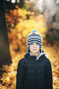 Portrait of boy standing against trees during autumn