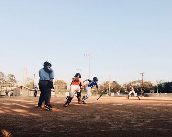 Children playing baseball against clear sky