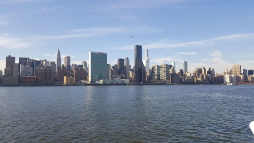 View of city at waterfront against cloudy sky