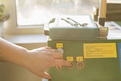 Cropped image of female mechanic's hand pressing button on machine in auto repair shop