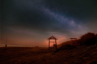 Lifeguard hut on beach against sky at night