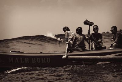 People on boat in sea against clear sky