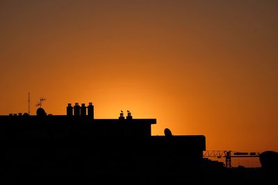 Silhouette buildings against sky during sunset