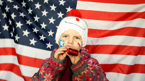 Close-up portrait of girl with party horn blower against american flag