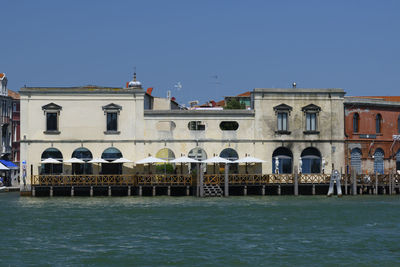 View of building by sea against clear blue sky