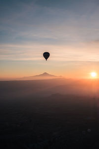 Hot air balloons flying against sky during sunset