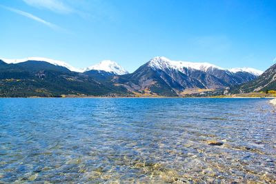 Scenic view of lake and mountains against blue sky