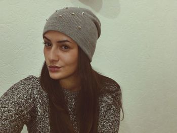 Beautiful young woman standing against wall at home