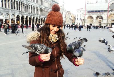 Beautiful woman feeding pigeons at town square