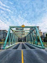 Road by bridge against sky in city