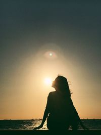 Silhouette woman standing on beach against sky during sunset