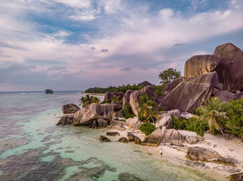 Rocks on shore by sea against sky