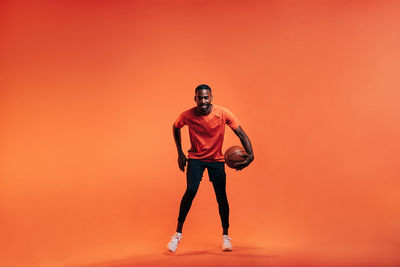 Full length of young man standing against orange sky