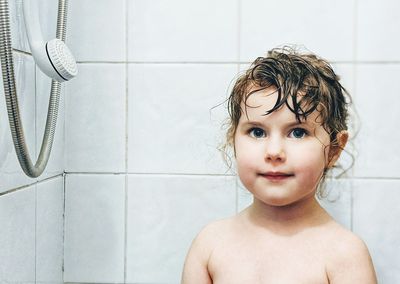 Portrait of shirtless boy against wall at home