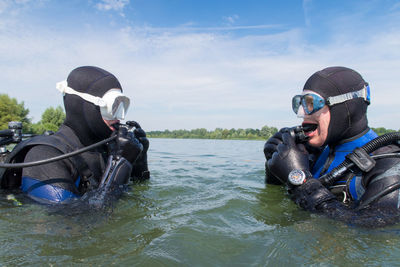 Young man and woman with diving suit in sea