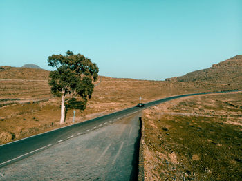 Road by trees against clear sky