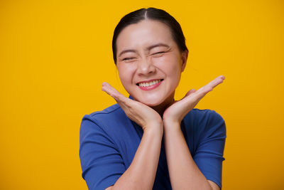 Portrait of a smiling young woman against yellow background