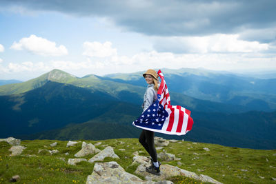 Rear view of man standing on mountain against sky