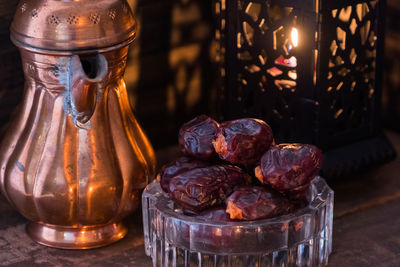 Close-up of antique teapot and lantern with raisins on table