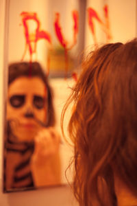 Reflection of woman with spooky face paint seen in mirror