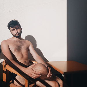 Portrait of young man sitting on seat at home