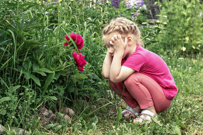 Side view of girl with pink flower on field