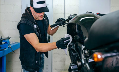 Mature mechanic cleaning motorcycle in garage